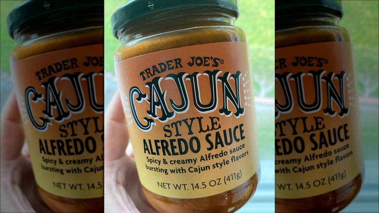 holding Trader Joe's Cajun-style alfredo sauce