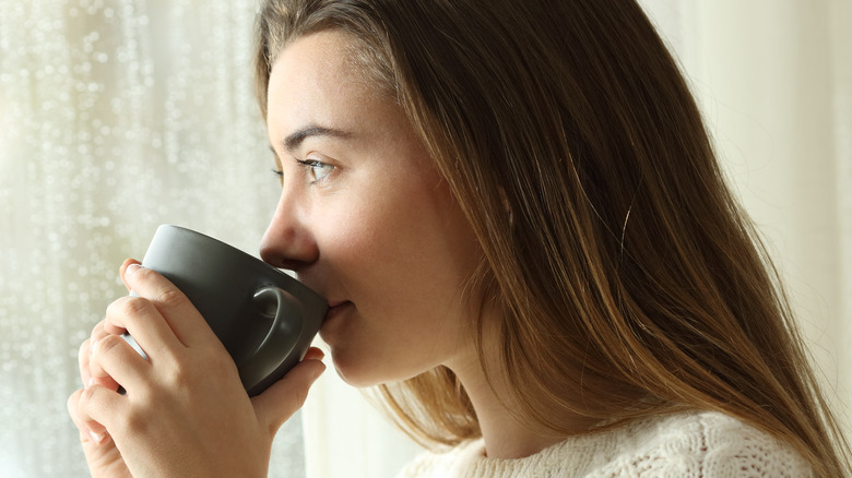 A woman sipping from mug