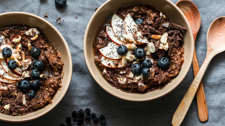 Two bowls of chocolate oatmeal topped with fruit