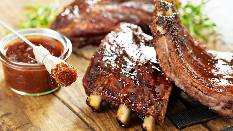 BBQ glazed ribs next to a grill brush with sauce