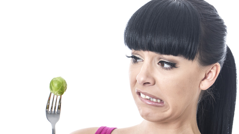 woman grimacing at Brussel sprout 