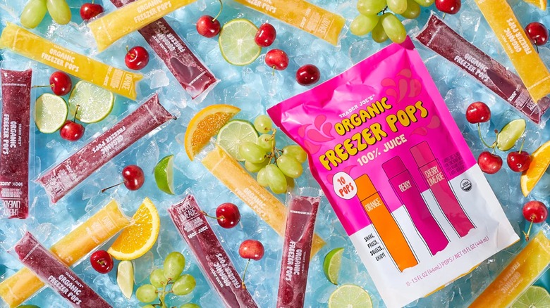 A bag of freezer pops on ice surrounded by individual freezer pops and assorted fruit.