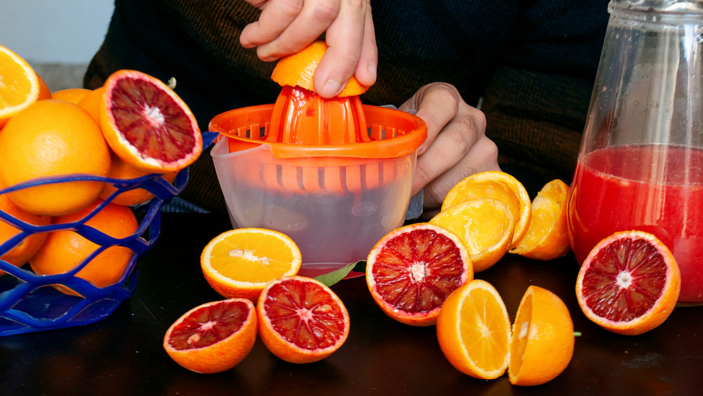 Squeezing blood oranges hand