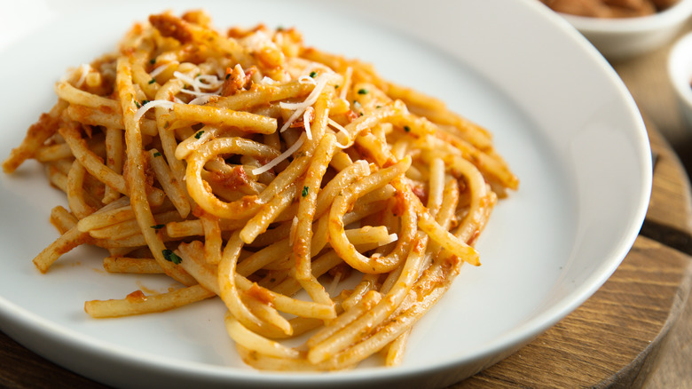 pasta with red pesto in white bowl