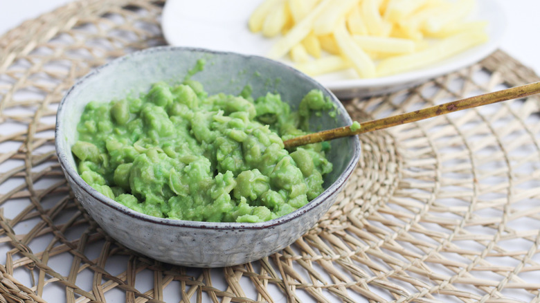 Bowl of mushy peas in front of plate of fries