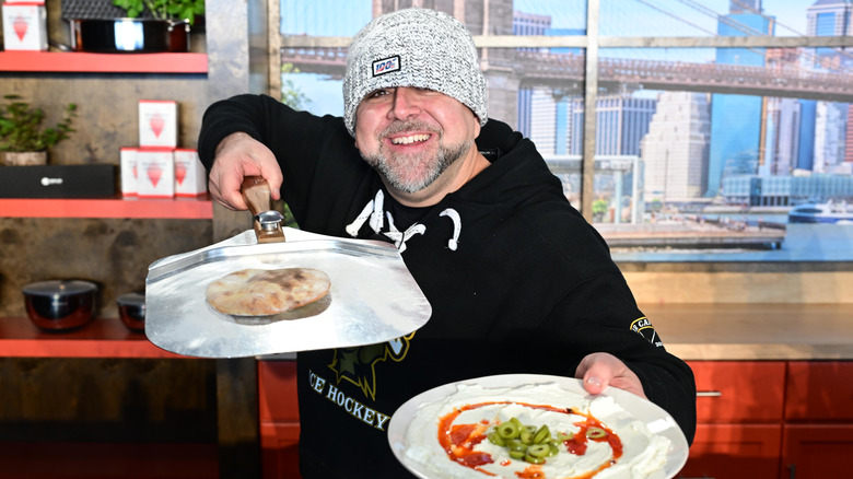 Duff Goldman holds two pans of food