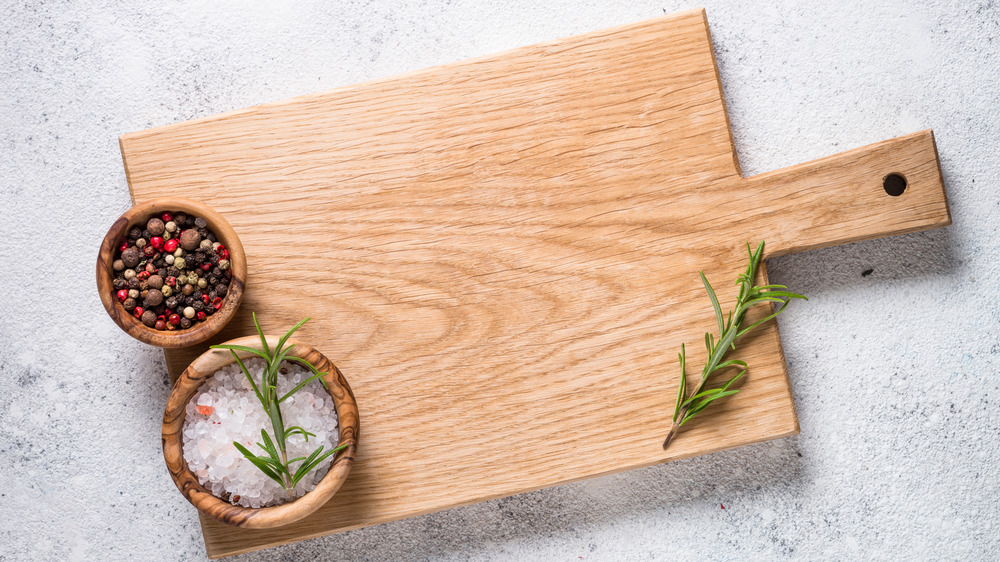 Wooden cutting board with salt, pepper, and herbs