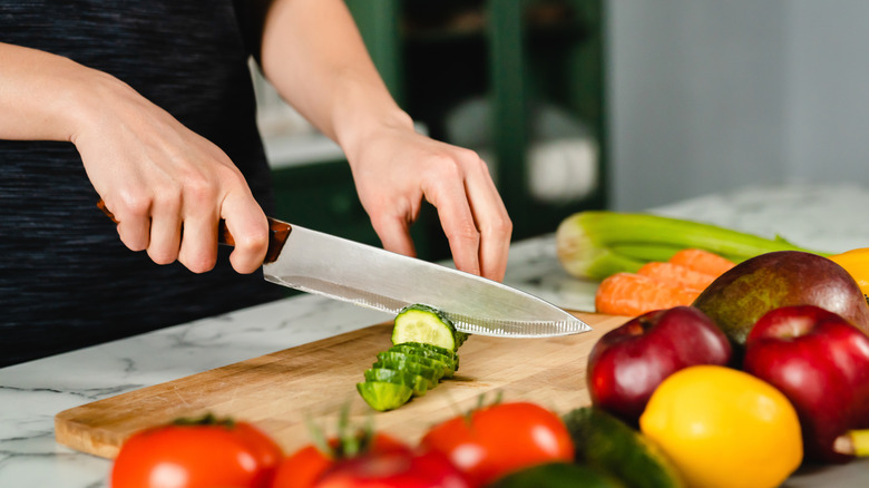 Hands slicing cucumber