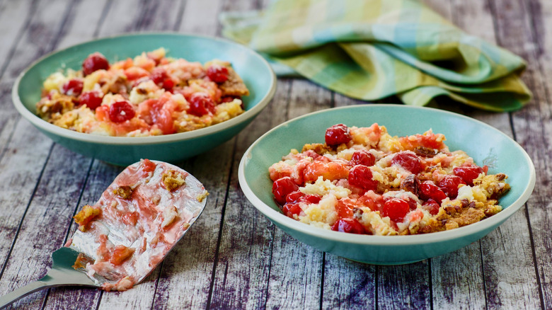 Two teal bowls of cherry dump cake with spatula