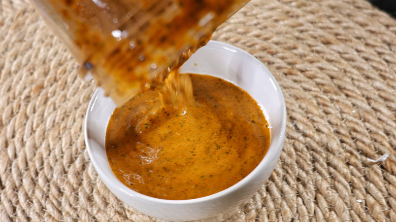 chimichurri rojo sauce pouring from blender into small white bowl