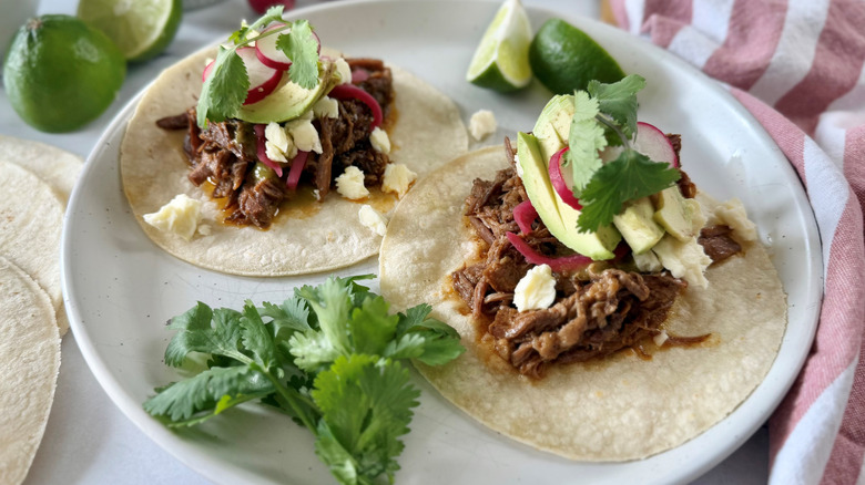 Brisket tacos with avocado, radishes, lime, and cilantro on plate