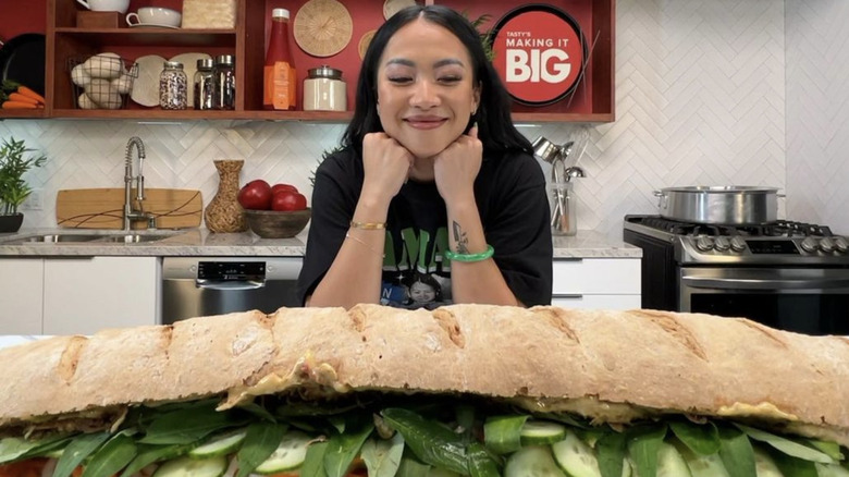 Tway Nguyễn smiling behind long sandwich