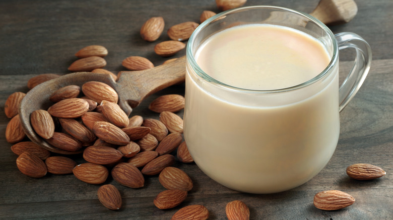 Almond milk in a cup next to almonds