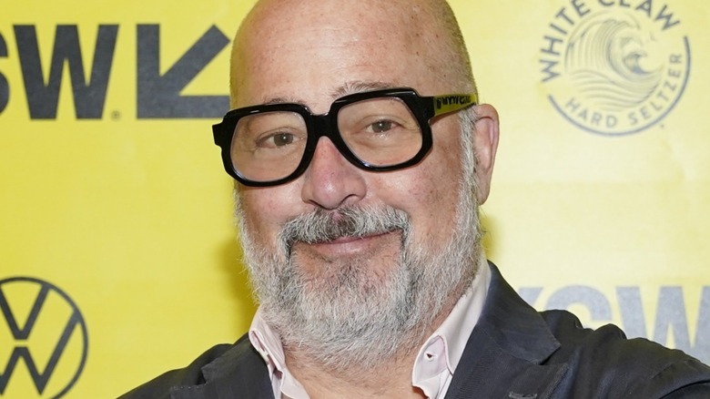 Andrew Zimmern smiling in black-rimmed glasses