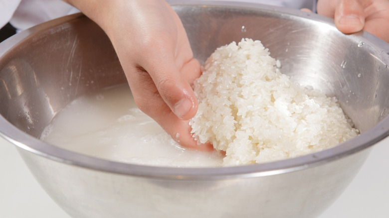 Hands washing rice in bowl
