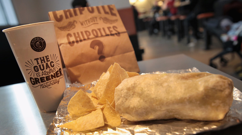 Chipotle burrito, chips and drink on a table