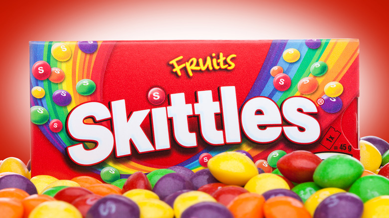 Box of Skittles amid loose candies