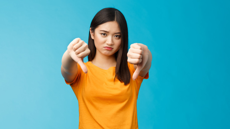Woman with downward pointing thumbs