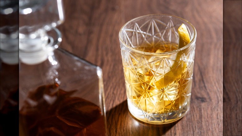 Rusty nail in a glass on a table next to a bottle of Scotch