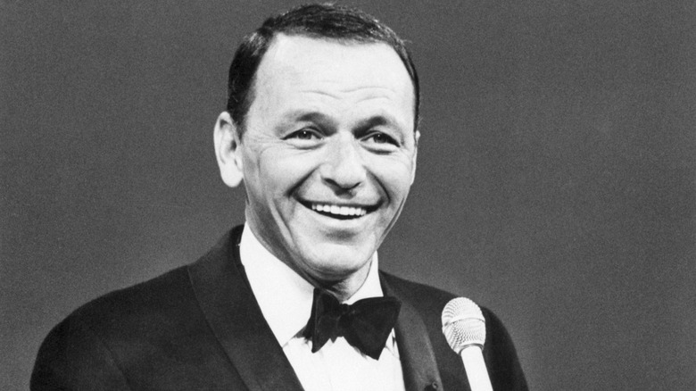 Frank Sinatra holding microphone in black and white photo