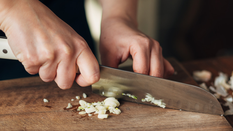 Person chopping garlic with knife on 