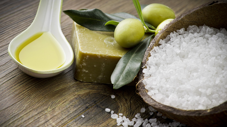 Olive oil in spoon next to small bowl of salt