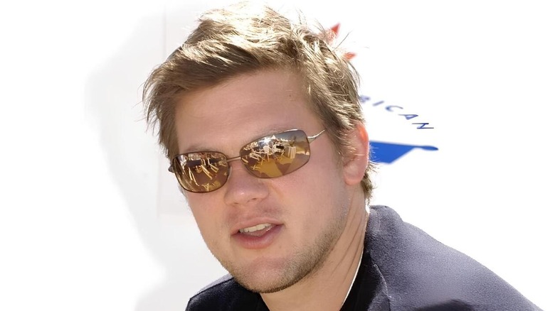Tyler Florence poses for a photo in a dark sweater and brown mirrored sunglasses