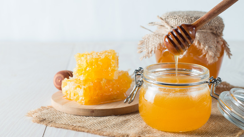 jar of honey with dipper and honeycomb