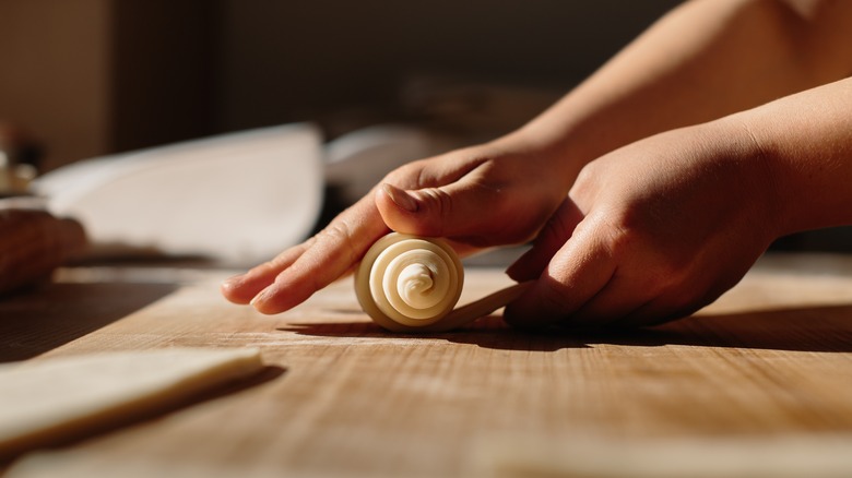 Rolling croissant dough on wooden board