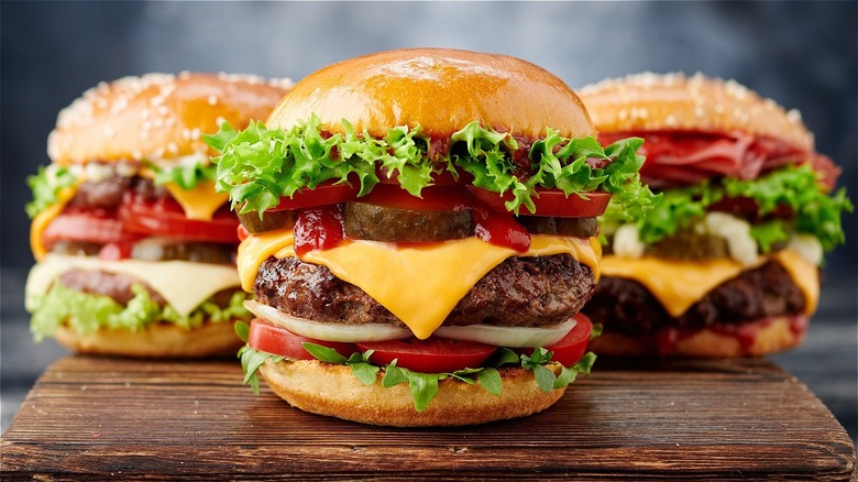 three hamburgers on wooden tray