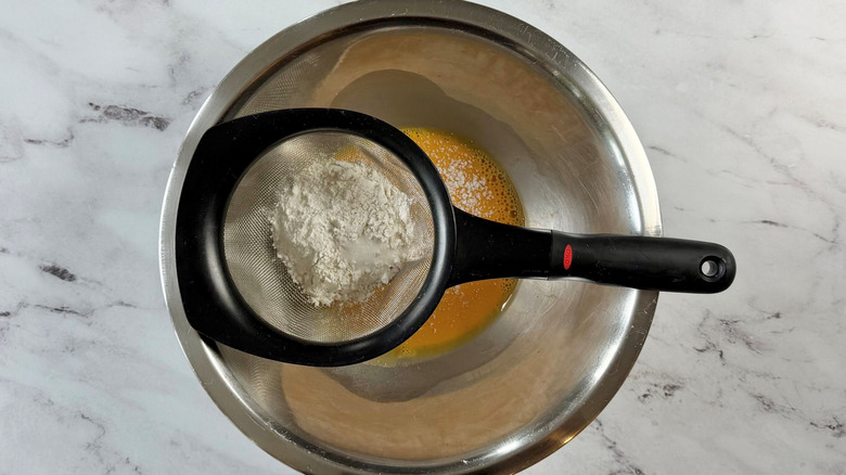 Sieve with flour sitting on top of bowl