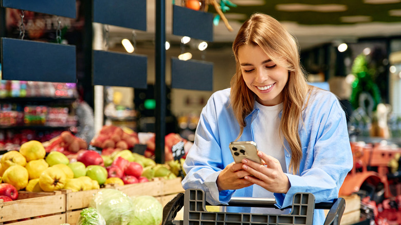 Smiling shopper walking past vegetables at the supermarket