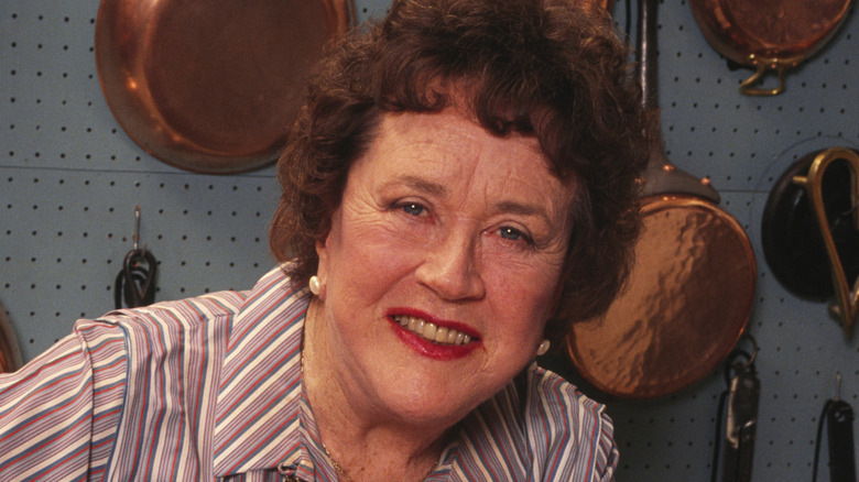 Julia Child smiling in kitchen.