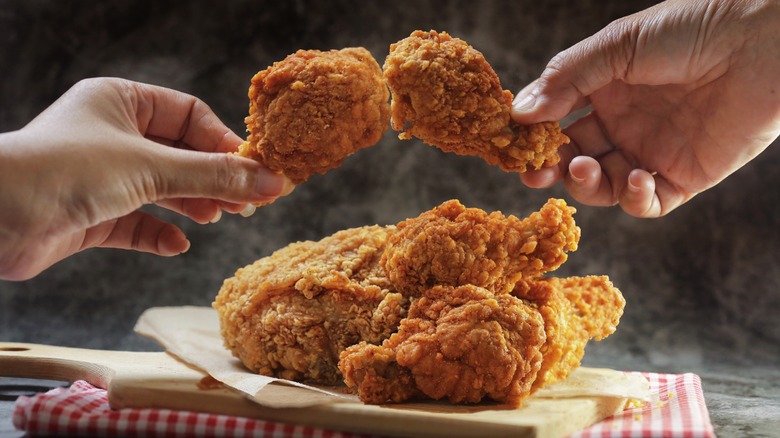 hands holding fried chicken