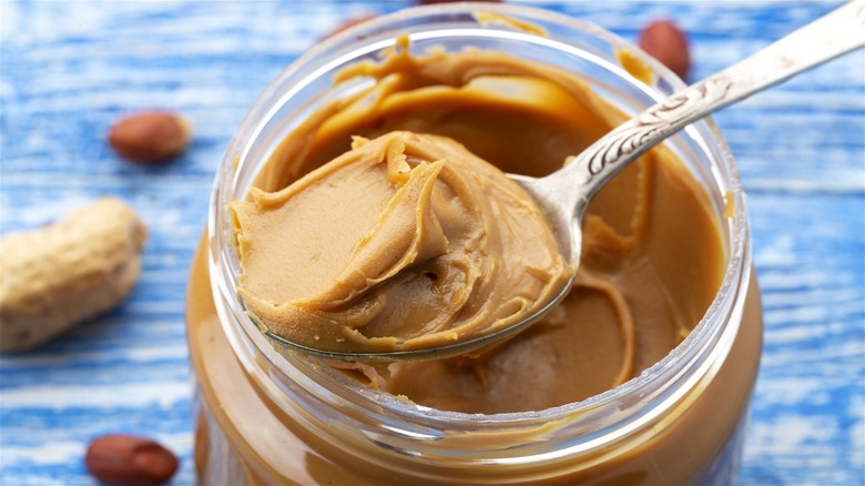 A spoon scooping out peanut butter from a jar.