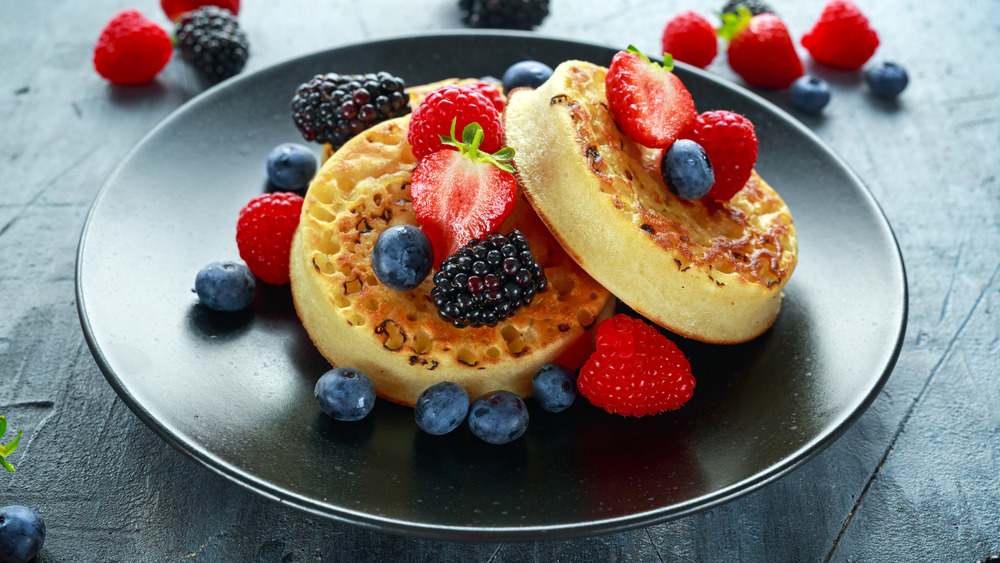 British Crumpets breakfast with blueberries, strawberries, blackberries, raspberries drizzled with icing sugar