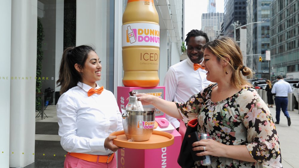 Dunkin' staff serving coffee on a tray in New York City