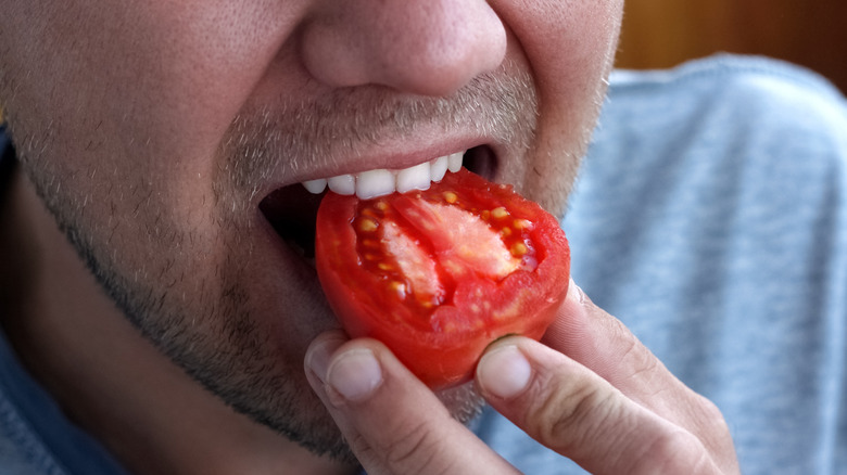 Person biting tomato slice