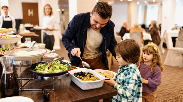 Parent helping two kids at buffet
