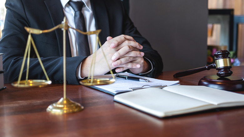 image of man in suit with hands crossed with justice scales