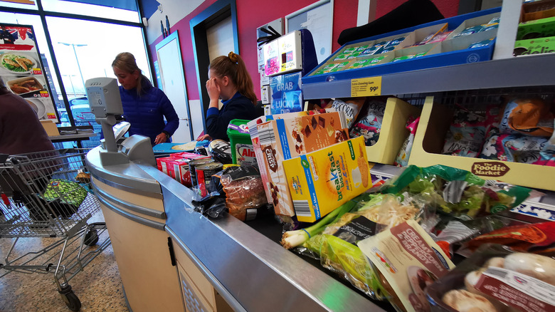 Aldi cashier sits at a register while ringing up items