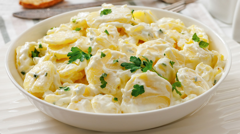 A bowl of potato salad topped with parsley leaves.