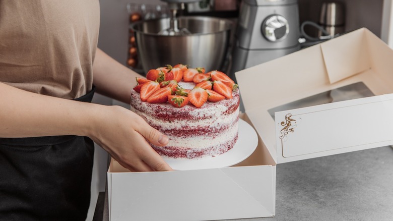 Cake being placed in a box.