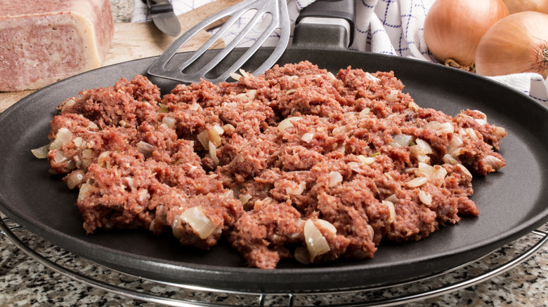 Cooking corned beef and onions in pan
