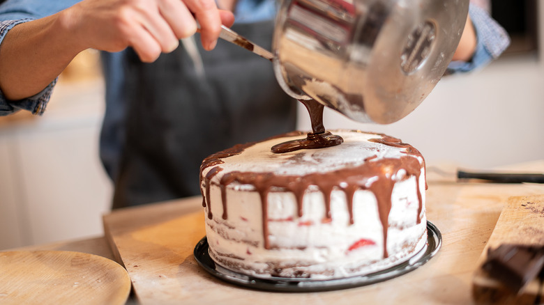 pouring frosting on a cake