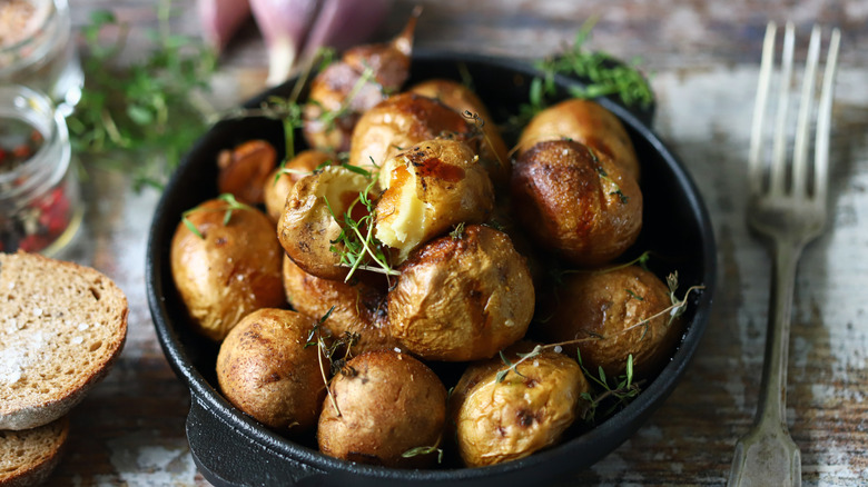 Oven-roasted baby potatoes with herbs, next to a couple pieces of toast, herbs, spices, and olive oil