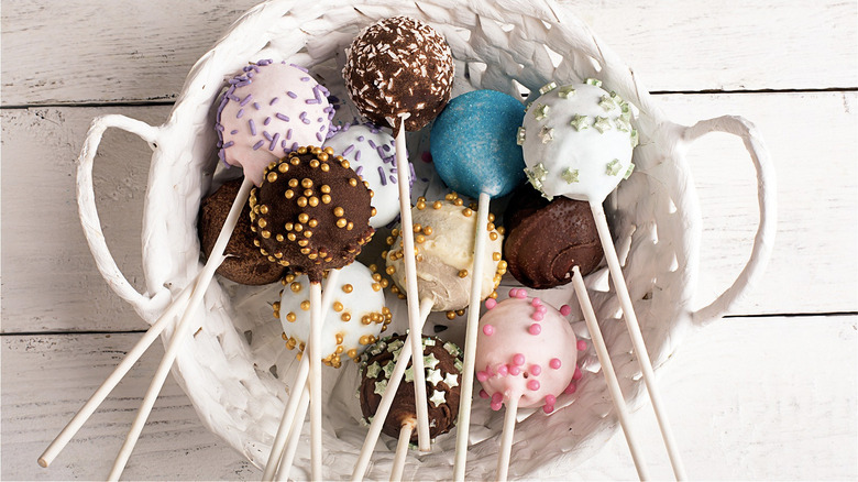 An assortment of cake pops pink, blue, purple with various sprinkles