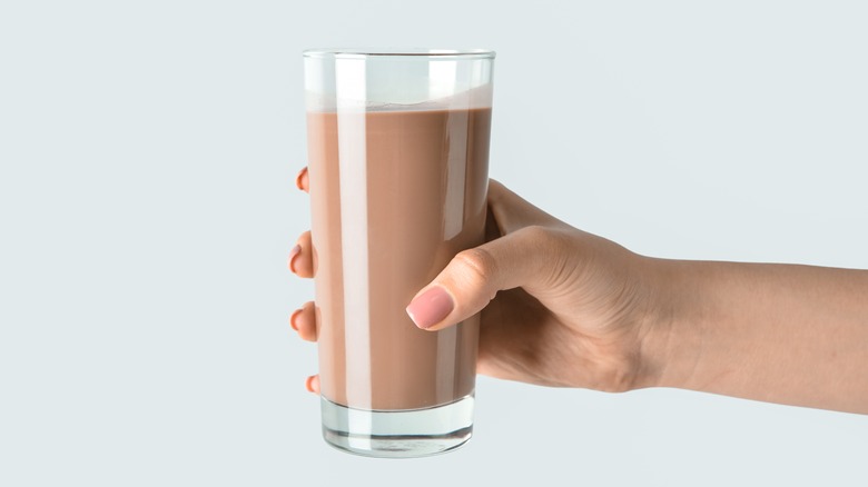 person holding glass of chocolate milk