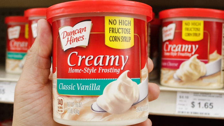 hand holding container of Duncan Hines frosting