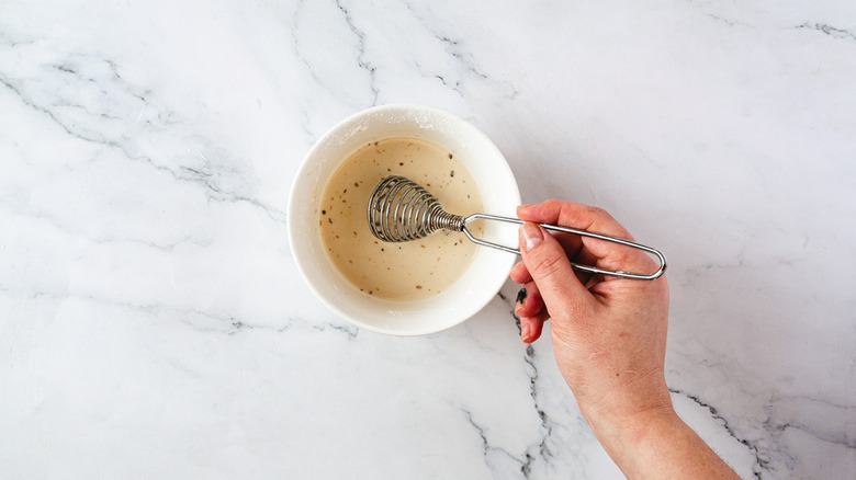 hand whisking cornstarch with water in bowl